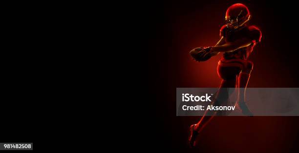 American Football Player With Ball On A Dark Red Background Stock Photo - Download Image Now