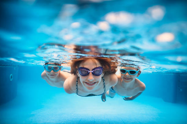 Three happy kids swimming underwater in pool