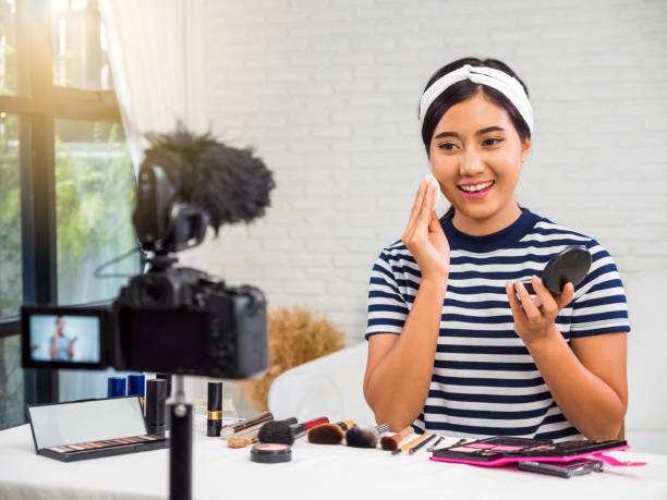 istock Young Asian beauty blogger present cosmetic product and recording her make up tutorial video to social network by internet at home 981488722