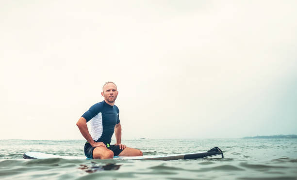 Man surfer sits on surf board in the water and  waits waves