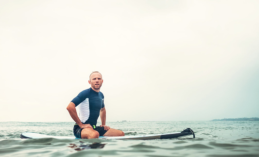 Man surfer sits on surf board in the water and  waits waves