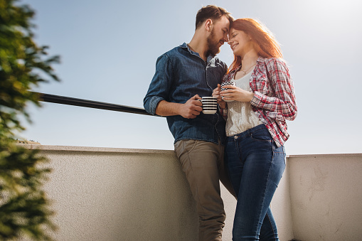 Low angle view of affectionate couple enjoying in their love on a terrace.