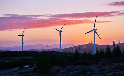 Wind turbines at sunrise in dramatic sky.