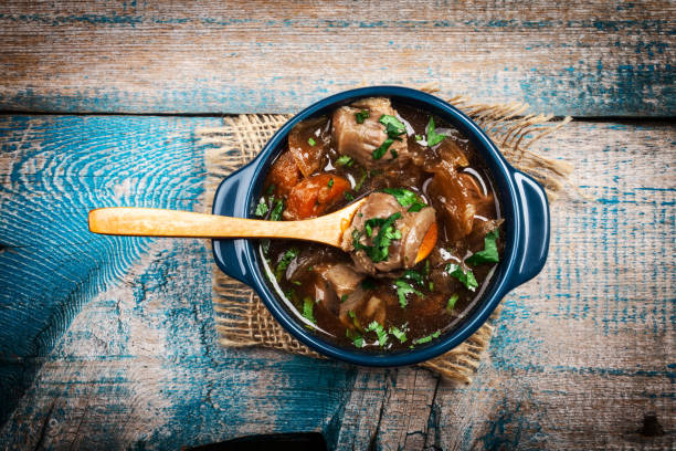 Ragoût de viande avec des légumes et des herbes sur la vieille table en bois - Photo