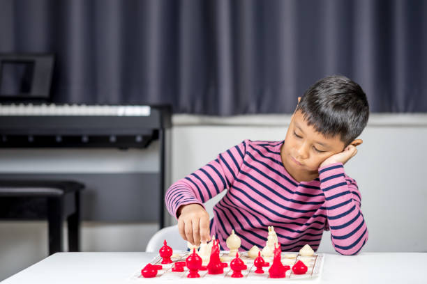 istock Young Asian boy playing chess in the room 981504734