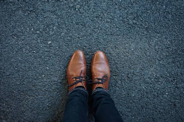 Little toddler boy with focus on dress shoes standing on concrete road