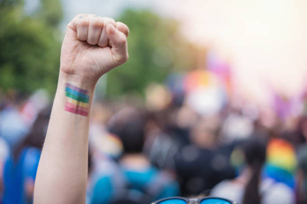 Raised up female arm with rainbow tattoo on it