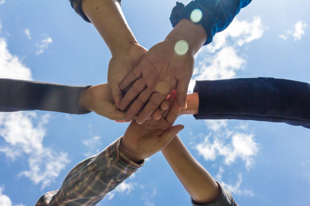 istock young business people putting their hands together, Sky background, Stack of hands. Unity and teamwork concept. 981513744