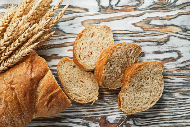 istock Sliced bread ripe rye ears on wooden surface 981517340