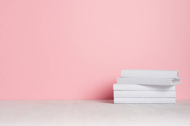 White blank books on white shelf and soft pink wall as modern, elegant home decor.
