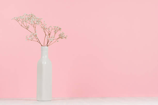 istock Small white dried flowers in elegant high ceramic vase on soft pastel pink background, copy space. Fashion home decor. 981526332