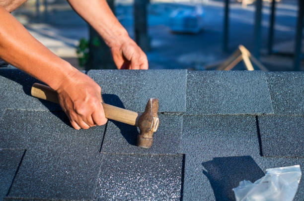 istock Roofer installing corner bitumen roof shingles with hammer and nails. 981526458