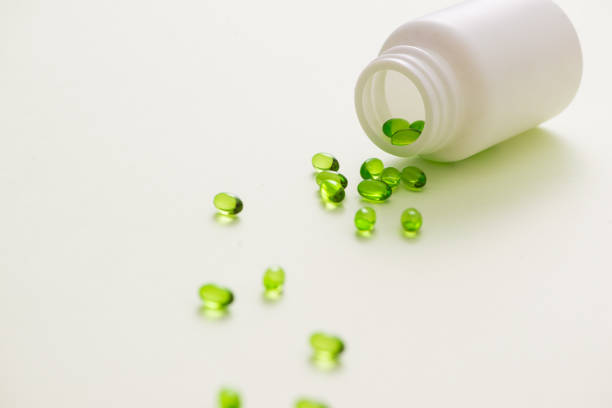 istock green capsules on a teaspoon isolated on white background 981527858