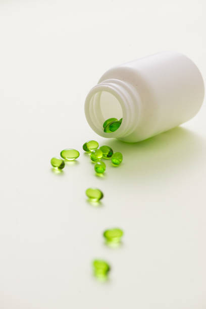 istock Green capsules in a bottle isolated on white background 981527864