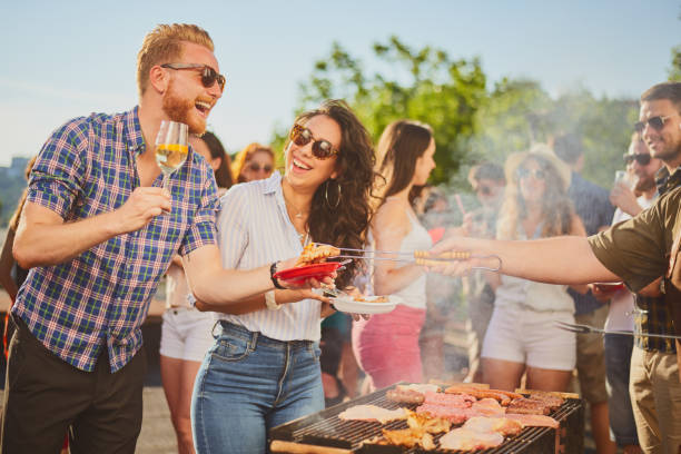 istock Group of people standing around grill. 981528978
