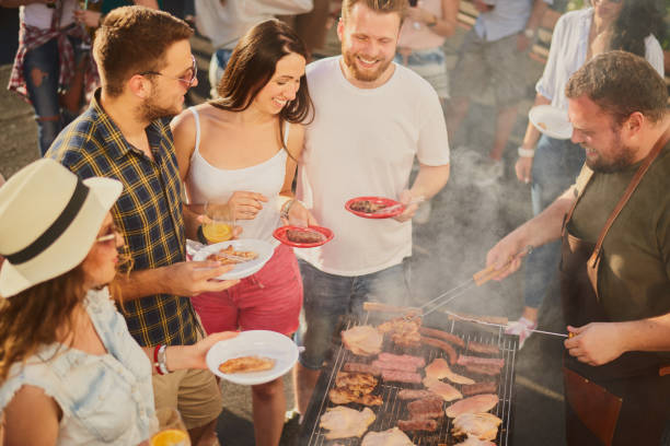 istock Group of people standing around grill. 981531736