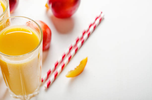 Juice from peaches and nectarines with pulp with fresh fruits on a white background. Copy space