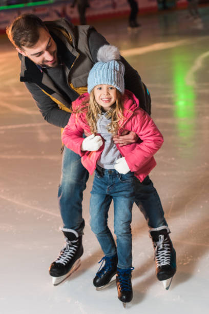 istock beautiful happy father and daughter hugging and having fun while skating on rink 981547886