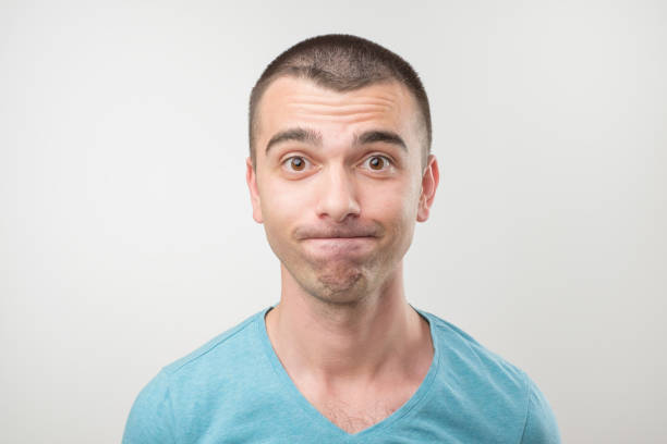 European man modest and embarrassed, isolated on gray background. He is shy and looking in camera with doubt