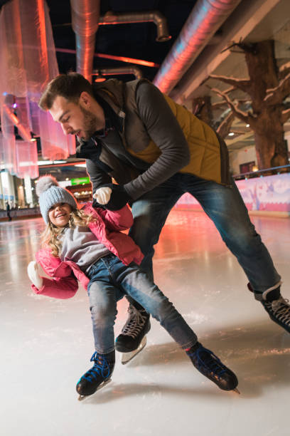 istock father teaching cute little daughter skating on rink 981580324