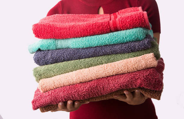 istock Woman holding stack of clean laundry towels. Isolated on white 981590318