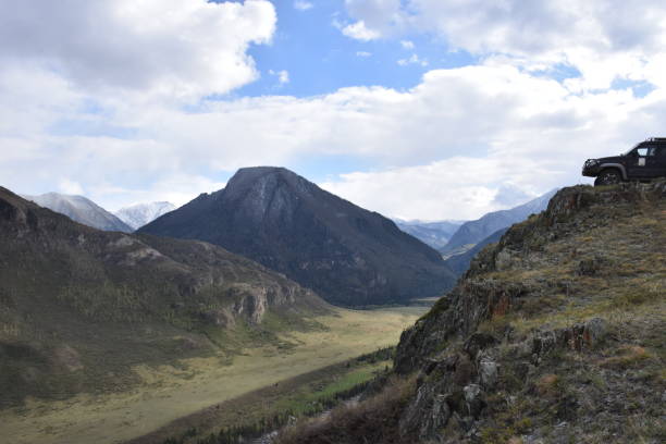 istock An SUV standing on a cliff with river valley below and mountains in the background 981595446