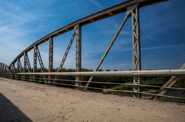 istock Old rusty railings on the bridge. Road with cracked asphalt 981595582