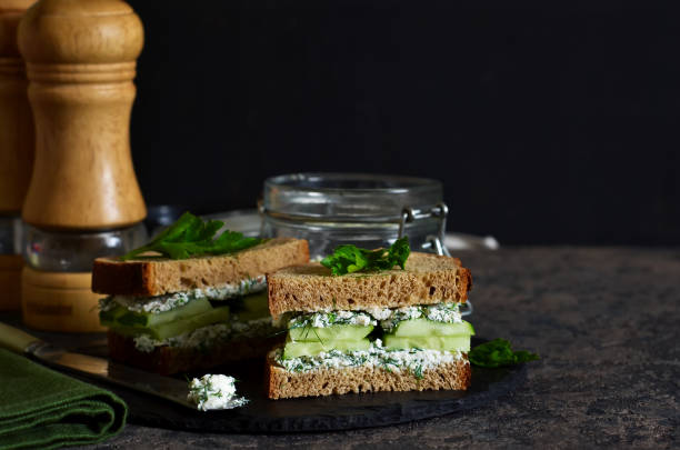 istock Vegan sandwich with cheese, cucumber and spices on a dark background. 981605636