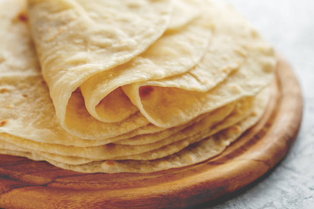 Stack of homemade wheat flour tortilla wraps on wooden cutting board. stock photo