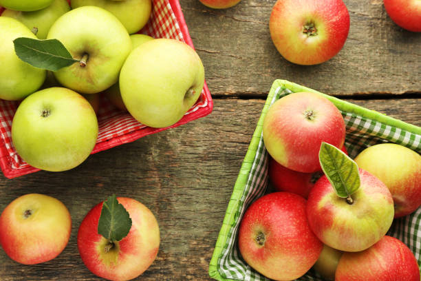 istock Ripe green and red apples in baskets on wooden table 981621612