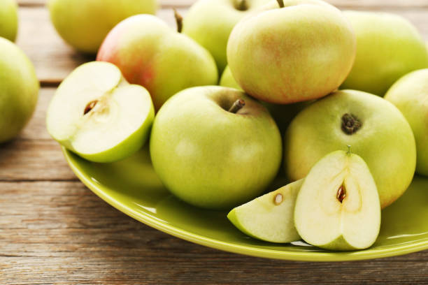 istock Ripe green apples in plate on wooden table 981626716