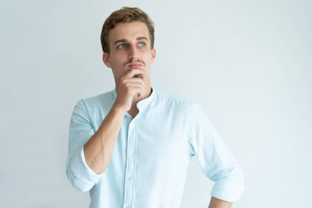 istock Pensive young man touching chin and looking away 981626742