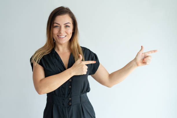 istock Smiling beautiful woman pointing aside with both forefingers 981626854