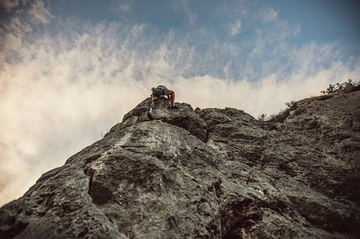 One man, disability young man with prosthetic leg free climbing on a rock in nature..