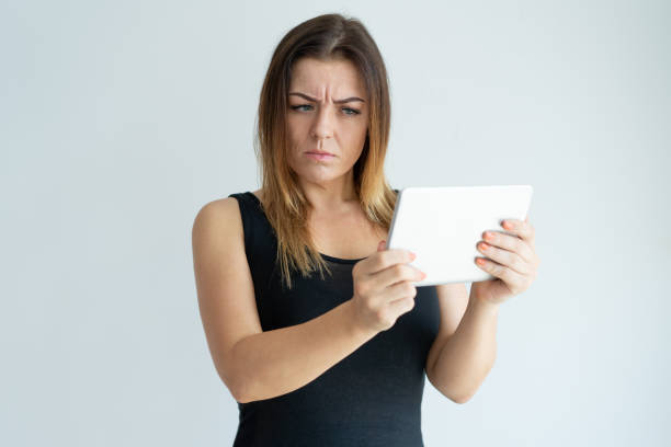 istock Skeptical pretty woman reading news on tablet computer 981626934