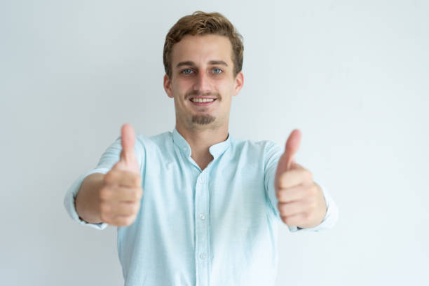 istock Smiling young man showing thumbs up and looking at camera 981627226