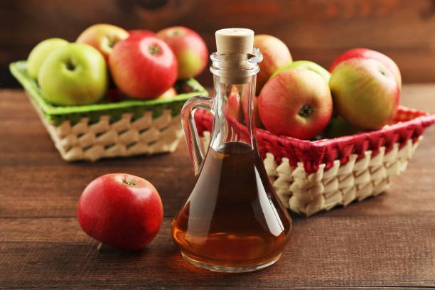 istock Apple vinegar in glass bottle on brown wooden table 981627336