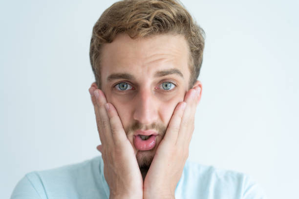 istock Worried young man looking at camera and touching cheeks 981627396
