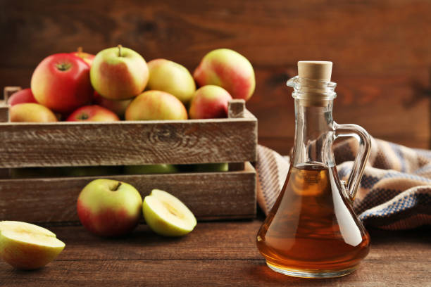 istock Apple vinegar in glass bottle on brown wooden table 981628152