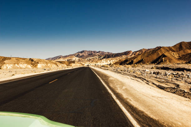 Shot of the road taken from the asphalt level with an abandoned car by the side.