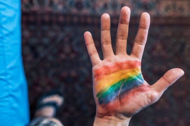 istock Man with a rainbow flag painted in his hand 981641720