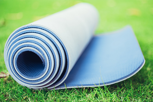 Close-up of folded purple yoga mat or foam mattress on lawn