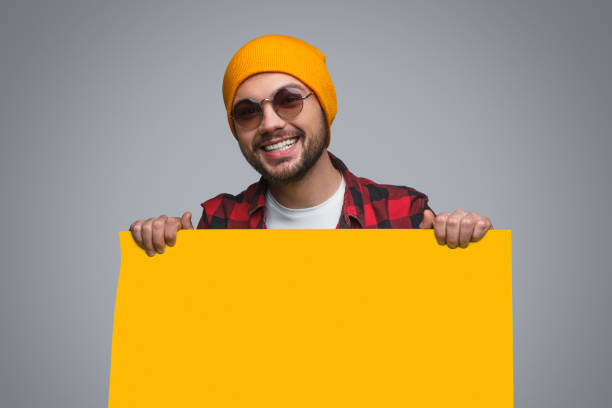 istock Stylish happy guy with yellow poster 981642984
