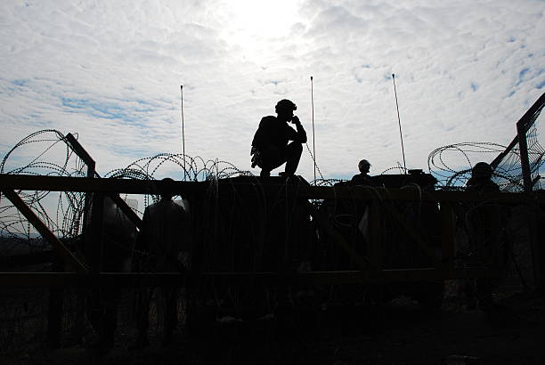 Military Silhouette Israeli soldiers guarding a barrier, silhouetted against afternoon sun barbed wire photos stock pictures, royalty-free photos & images