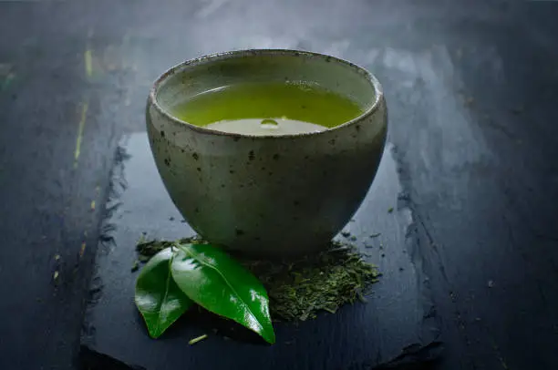 hot green tea in a traditional bowl on a dark background
