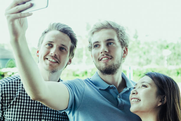 Positive young friends taking selfie in park