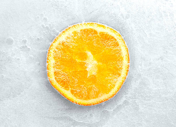 Crosscut of an orange frozen inside of ice stock photo