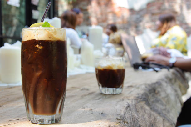 The espresso iced coffee. The espresso coffee with ice cube that mixing sweeten soft drink to enjoy hot weather of the summer with the background of cafe with old brick wall that have space for text and background. brick cafe stock pictures, royalty-free photos & images