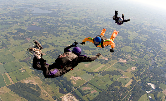 Three skydivers completing a freefall formation.