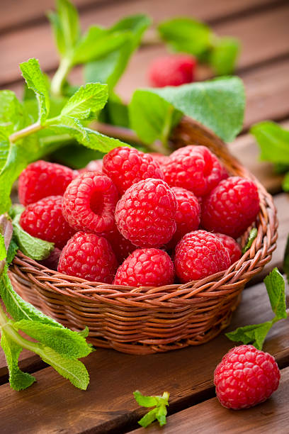 istock Fresh and ripened raspberries with greens in small basket 98168253